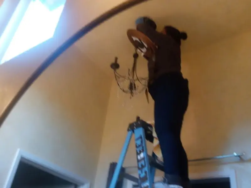 Electrician installing a chandelier in a La Riviera residence